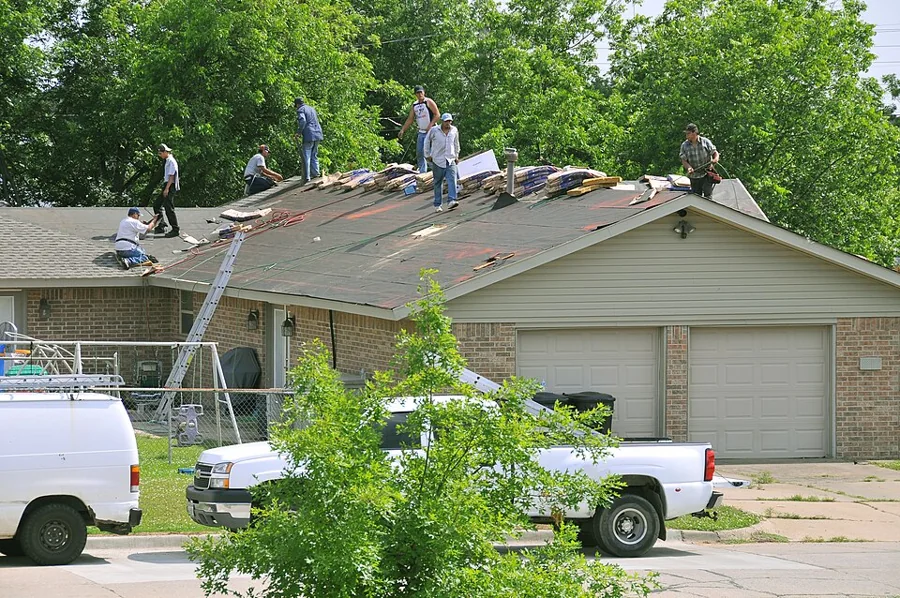 Roofing crew tearing off and replacing a residential roof