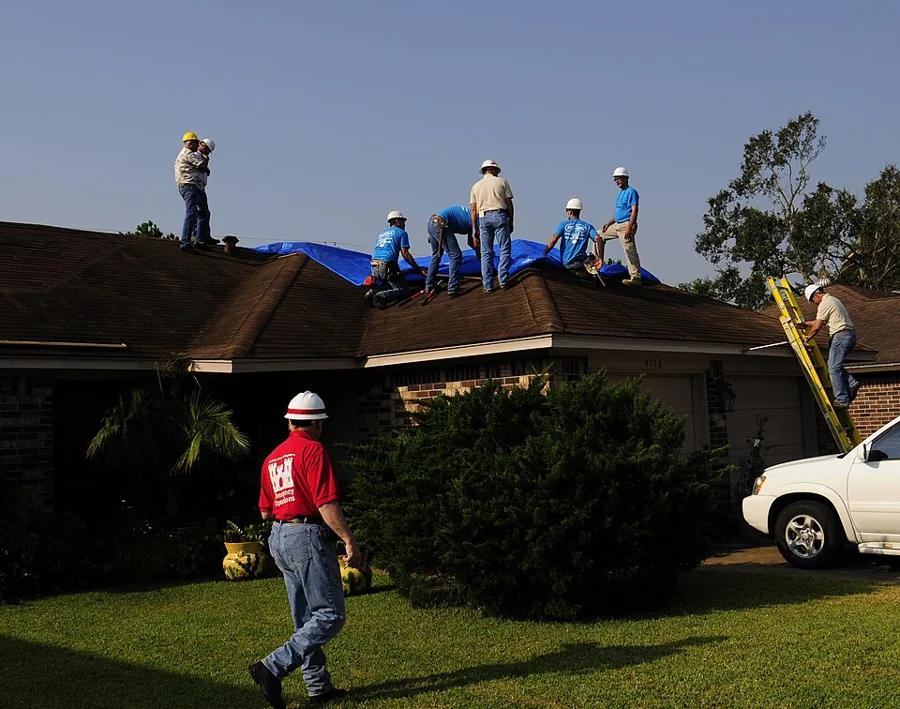 Roofers working across a large residential roof