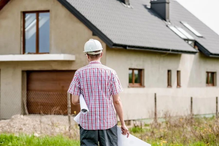 A contractor with plans looking over a house